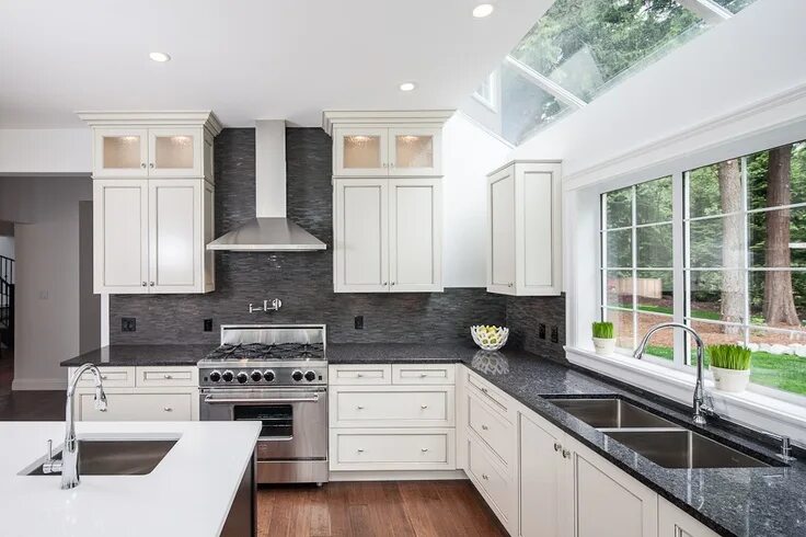 Кухня с темным фартуком фото The kitchen island features Kitchen Craft's 'Lexington' doorstyle in Maple. Blac