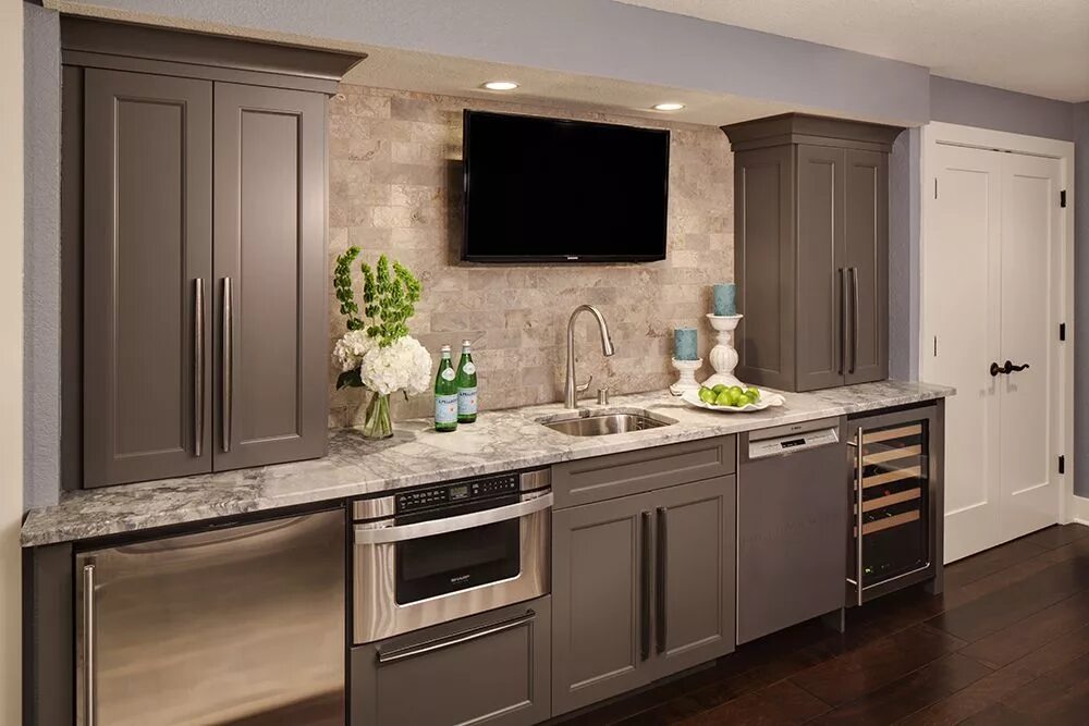 Кухня тауп в интерьере Lower level remodel with a wet bar, featuring marble subway tile, leather-textur