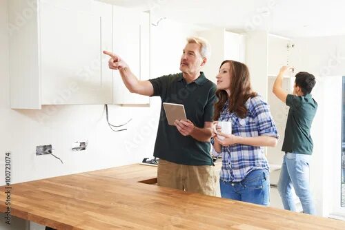 Квартира посредник фото Woman With Carpenter Looking At Plans For Kitchen On Digital Tab фотография Stoc