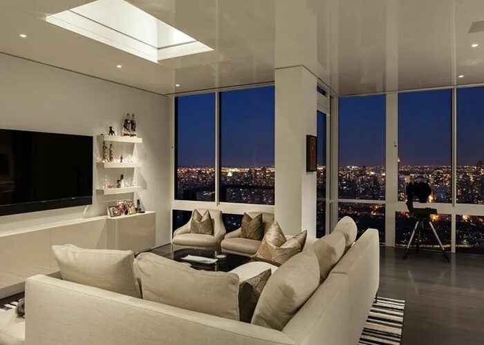 Квартира в сити фото View of the living room at night with the bright lights of NYC Skyline in the ba