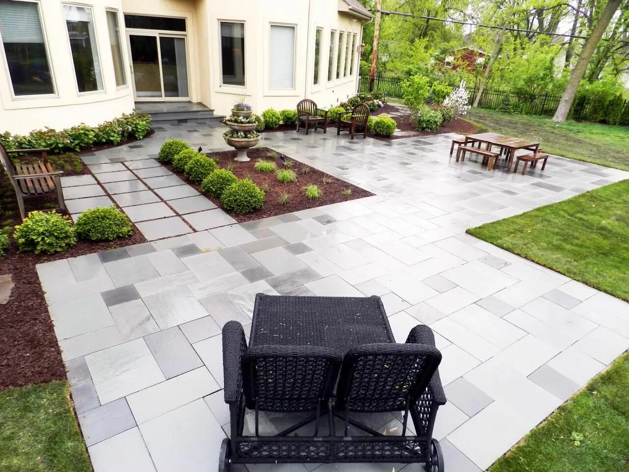 Плитка на участке частного дома фото Easily maintained landscaping and a sleek stone patio create a contemporary spac
