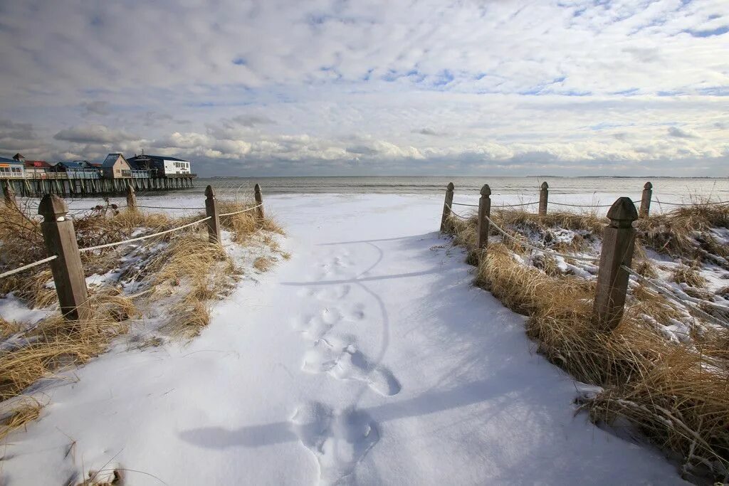Пляж зимой фото Snow coats the sand at an entrance to the beach in Old Orchard Beach in January.