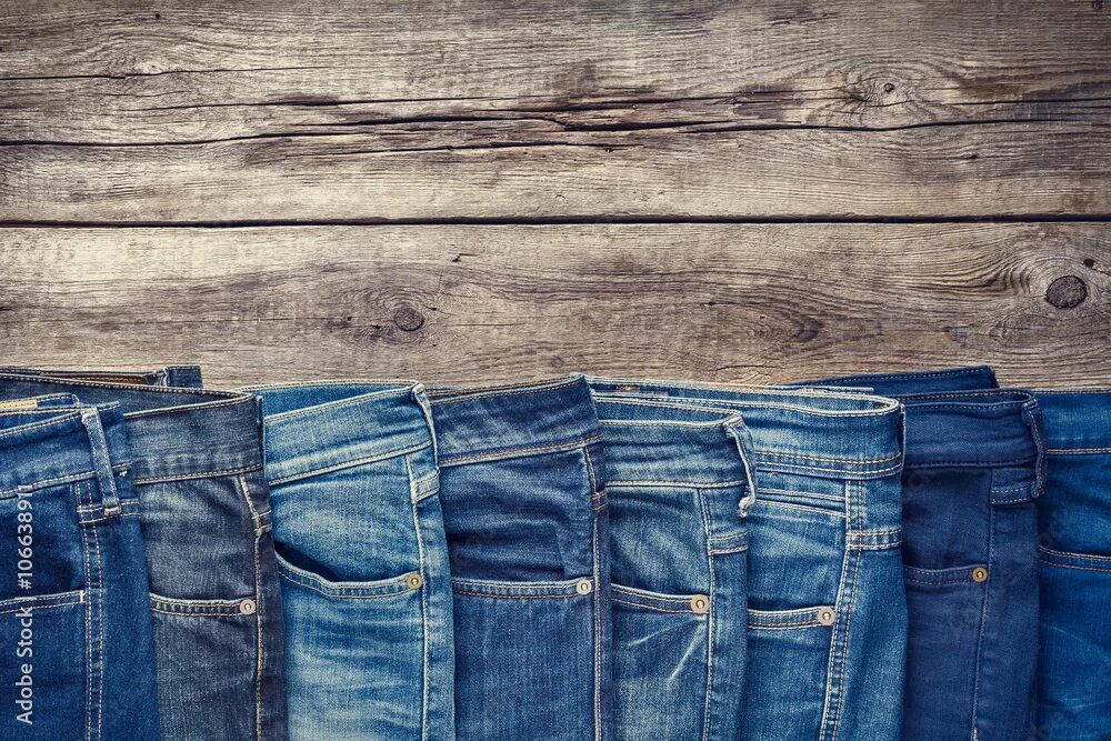 Под джинс фото Fashion different jeans on wooden background. Retro toned. фотография Stock Adob