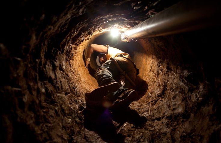 Под землей фото An illegal miner uses a rudimentary pulley to descend into a hole dug in search 