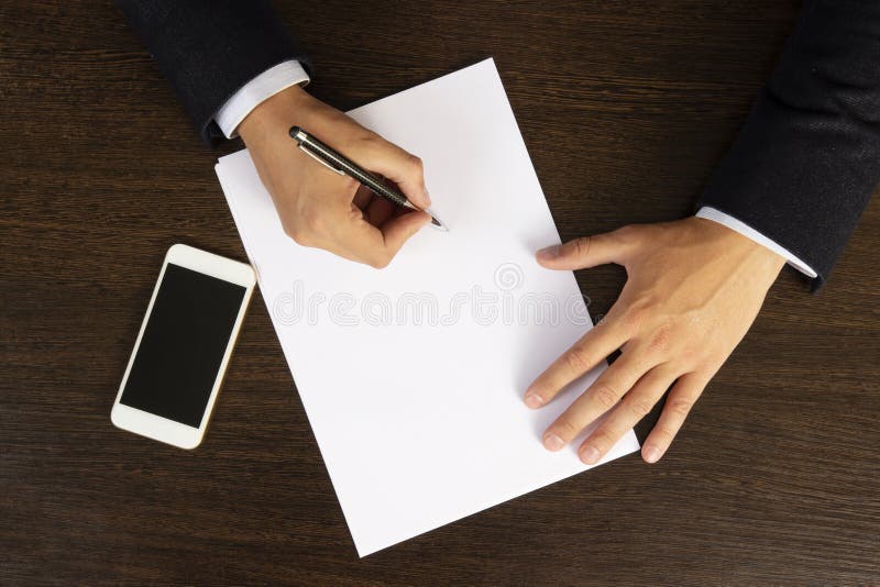 Подписывает бумаги фото Businessman in Suit Writes on White Sheet of Paper Top View. Work Desk of an Off