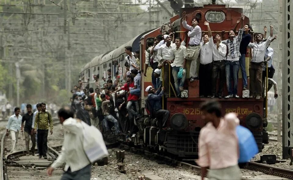 Поезд в индии с людьми фото Commuters travel standing on a train engine of an overcrowded local train in Mum