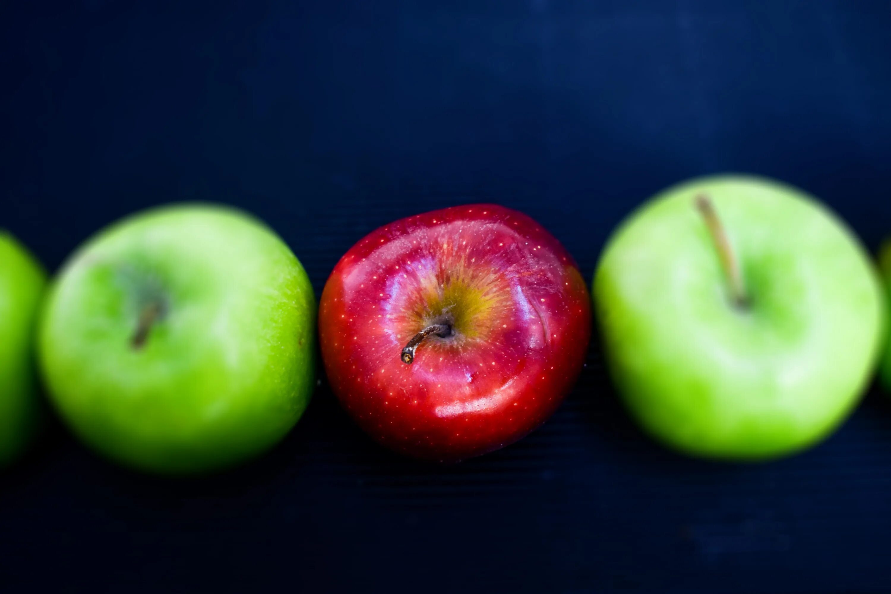 Покажи фото яблока Red Apple among green ones at dark background free image download