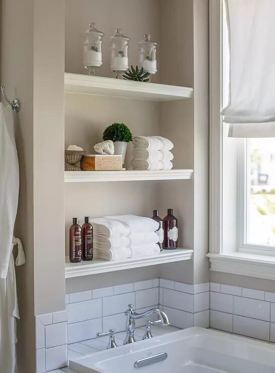 Полки в ванной фото White stacked floating shelves are mounted in a nook above a drop in bathtub fit