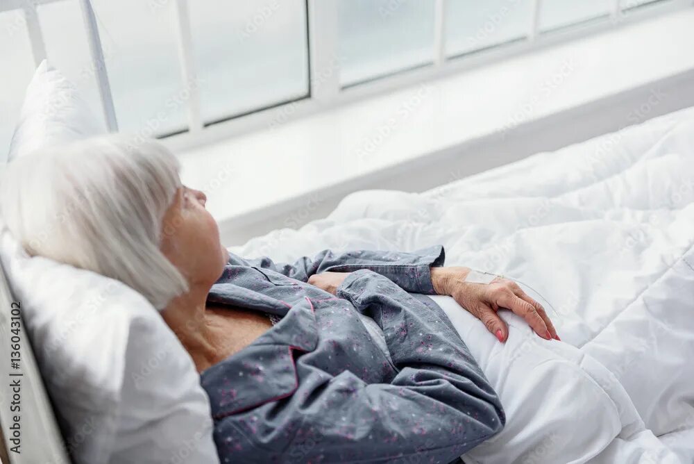 Пожилые женщины на кровати фото Serene old woman lying on cot in hospital apartment фотография Stock Adobe Stock