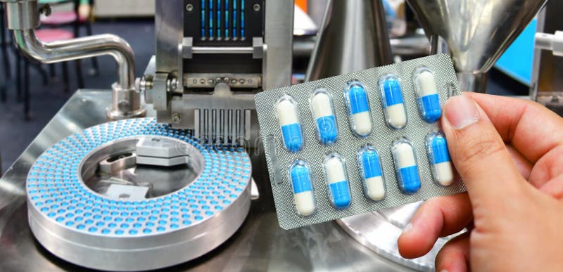 Производство таблеток фото Hand Holding Blue Capsule Pack at Medicine Pill Production Line Stock Image - Im