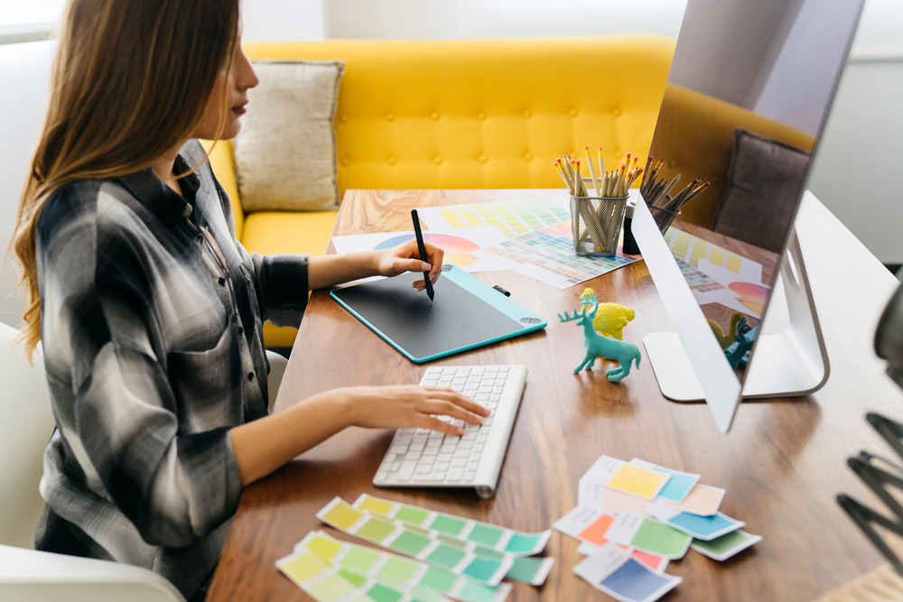 Interior designer sitting at desk and looking at printed photos of clients rooms