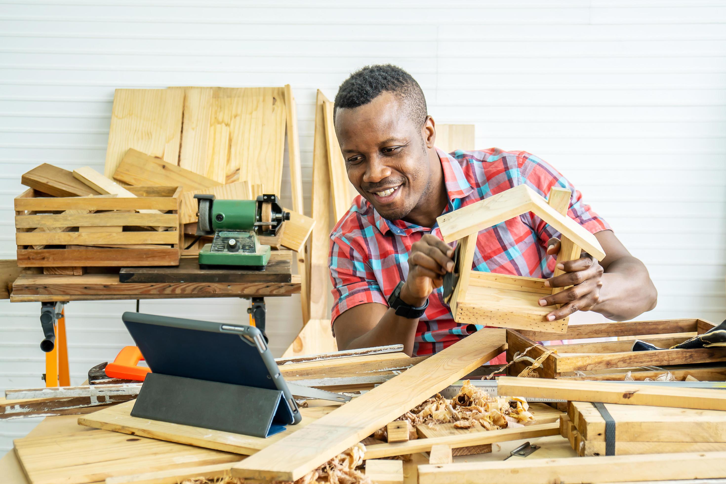 Работы плотников фото Young african american male carpenter sitting at table showing wooden items thro