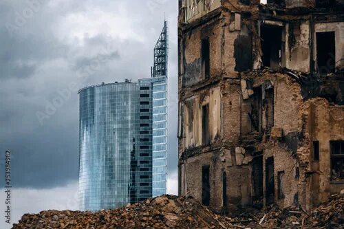 Распознать здание по фото A new modern glass skyscraper and a destroyed old building. фотография Stock Ado