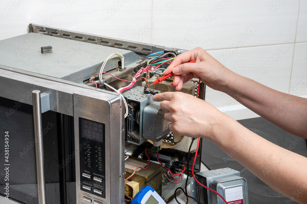 Ремонт микроволновую своими руками Repair of the microwave oven. A woman measures the electrical characteristics wi